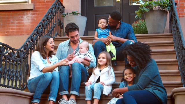 Two families with kids sitting on front stoop in Brooklyn